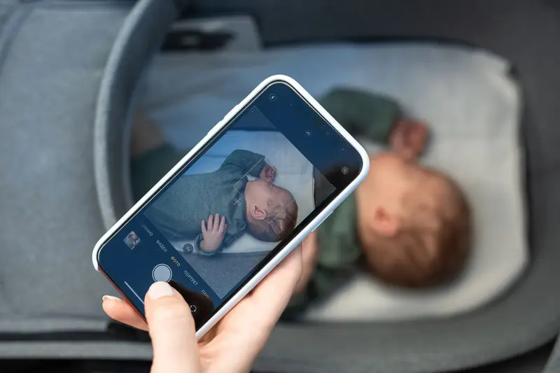 A smartphone capturing a peaceful newborn baby sleeping in a crib, highlighting modern parenthood
