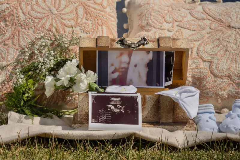 A vintage box with ultrasound photos, baby items, and floral decor captures a heartfelt gender reveal moment