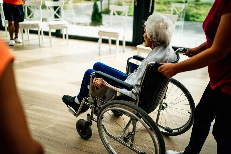 A caregiver assists a senior adult in a wheelchair at a nursing home in Prague, Czech Republic