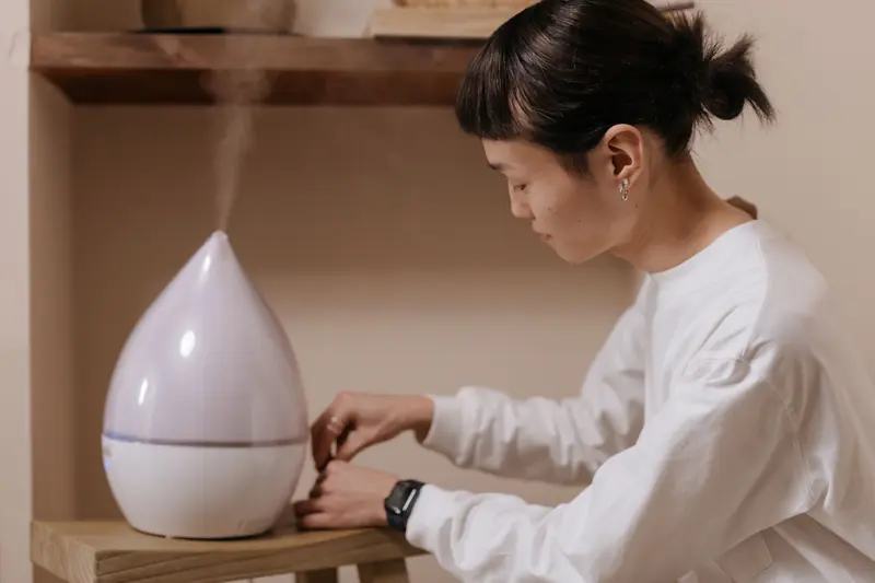 A woman adjusts a humidifier indoors, promoting relaxation and air quality