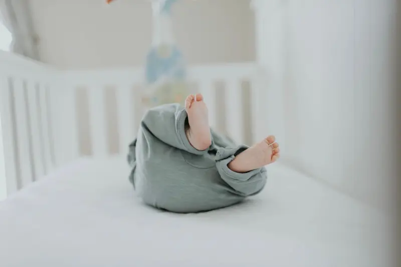 Cute baby feet in pajamas on a soft white crib. Perfect for children's room decor