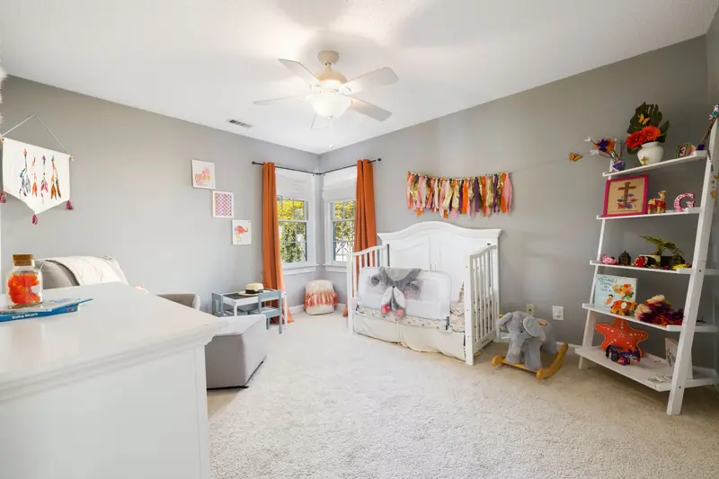 A spacious nursery room featuring a crib, playful decor, and bright natural light