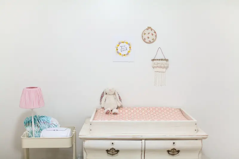 A cozy and minimalist baby nursery featuring a changing table and plush toy
