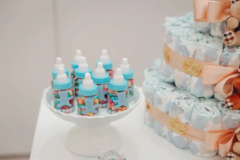 Colorful candies in baby bottles and a decorated diaper cake for a baby shower