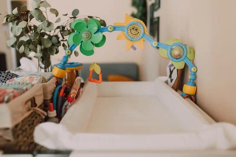 A baby changing table with toys and decor in a cozy nursery, featuring colorful elements and indoor plants
